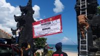 SPANDUK PANTAI-1 PETUGAS memasang spanduk peringatan penutupan kawasan Pantai Jimbaran untuk menghentikan penyebaran pandemi Covid-19. Foto: istimewa