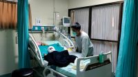 LUH Tasya Devi Juniantari (4) yang terbaring di ruang perawatanRSUD Buleleng, saat dijaga ayahnya. Foto: rik LUH Tasya Devi Juniantari (4) yang terbaring di ruang perawatanRSUD Buleleng, saat dijaga ayahnya. Foto: rik