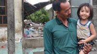 Wayan Mara saat menggendong cucunya yang selamat dari reruntuhan tembok akibat gempa.