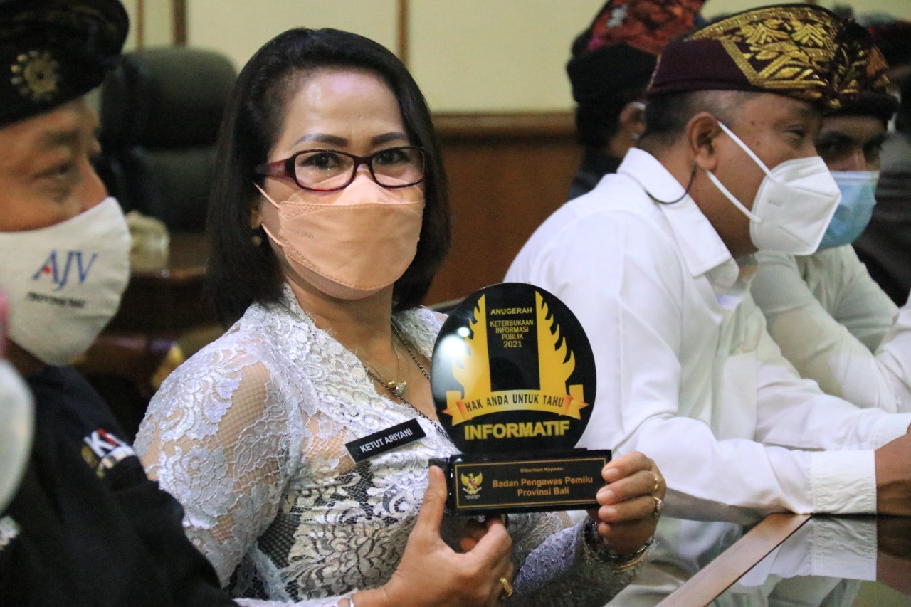 KETUA Bawaslu Bali, Ketut Ariyani, menunjukkan penghargaan Predikat Informatif yang diberi Komisi Informasi Provinsi Bali, Kamis (9/12/2021). Foto: ist