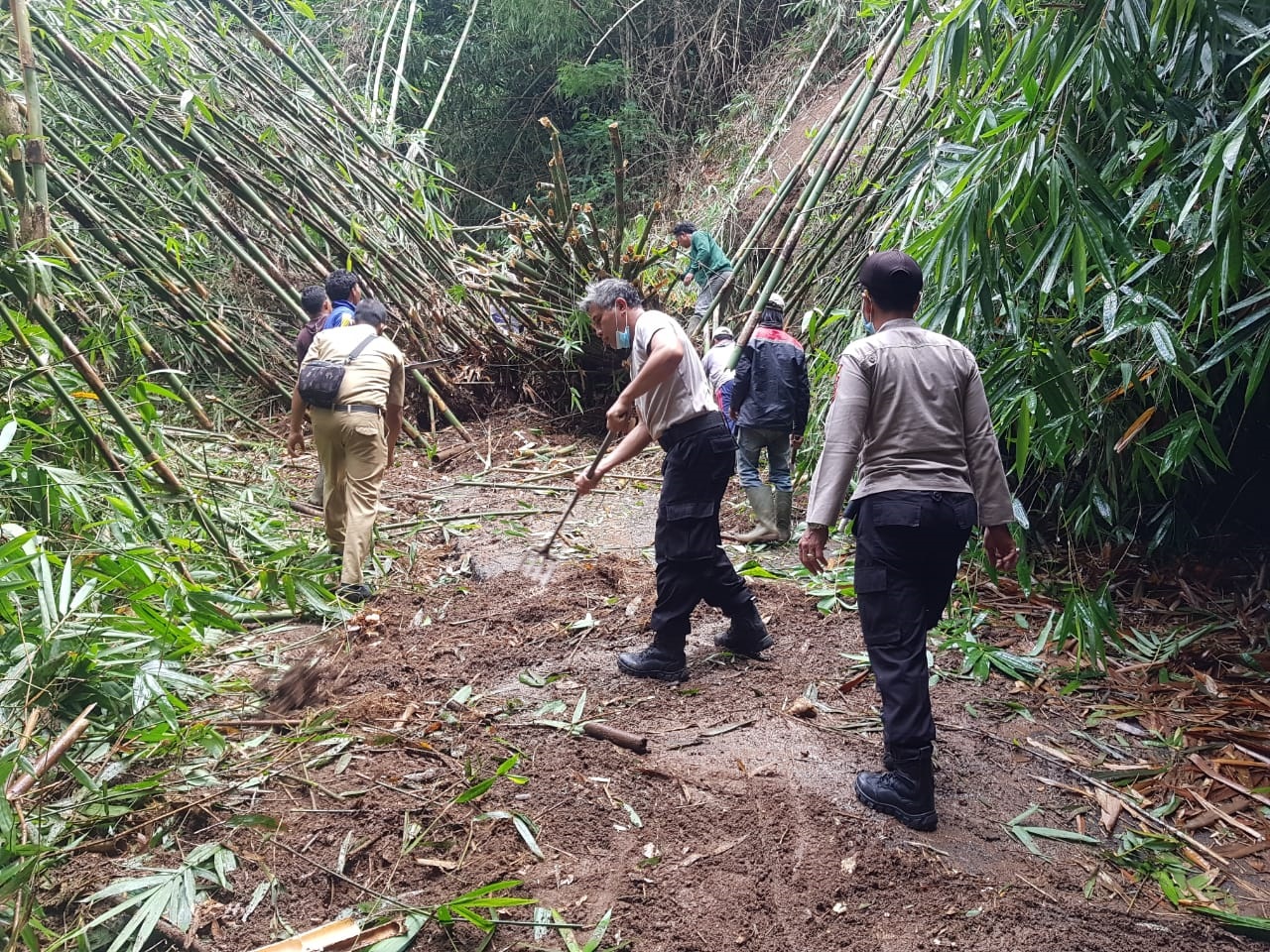 PETUGAS kepolisian dan warga berusaha menyingkirkan material longsor dan pohon tumbang yang sempat melumpuhkan jalur Desa Tiga-Banjar Temaga, Kecamatan Susut, Bangli. Foto: gia