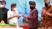 Gubernur Koster tampak menyerahkan tumpeng saat HUT ke-70 MGPSSR di Gedung Ksirarnawa