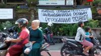 SPANDUK bertuliskan penolakan terhadap kepemimpinan Kepala sekolah bertebaran di pasang di depan pagar SMPN 5 Denpasar, Jumat (21/10/2022) pagi.