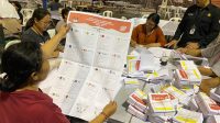 SALAH seorang tenaga pelipat suara di gudang logistik KPU Denpasar memeriksa surat suara sebelum melipatnya. Foto: ist SALAH seorang tenaga pelipat suara di gudang logistik KPU Denpasar memeriksa surat suara sebelum melipatnya. Foto: ist