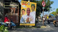 PENGENDARA motor melintas di depan baliho Gde Oka yang dipasang di Jalan Tunjung Sari, Denpasar Barat dengan mencantumkan sebagai calon Wali Kota Denpasar 2024-2029. Foto: hen PENGENDARA motor melintas di depan baliho Gde Oka yang dipasang di Jalan Tunjung Sari, Denpasar Barat dengan mencantumkan sebagai calon Wali Kota Denpasar 2024-2029. Foto: hen